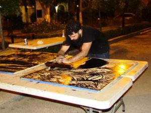 Demostración pública de la impresión de pendones con la técnica de aplanadora sobre madera